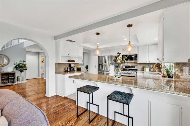 kitchen with stainless steel appliances, a raised ceiling, sink, and white cabinets