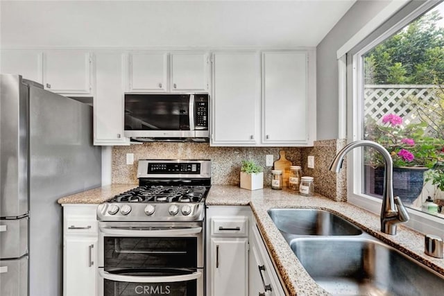 kitchen with backsplash, appliances with stainless steel finishes, sink, and white cabinets