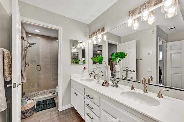 bathroom with wood-type flooring, toilet, an enclosed shower, and vanity