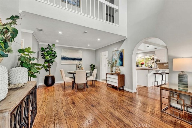 foyer entrance with light hardwood / wood-style flooring, ornamental molding, and a high ceiling