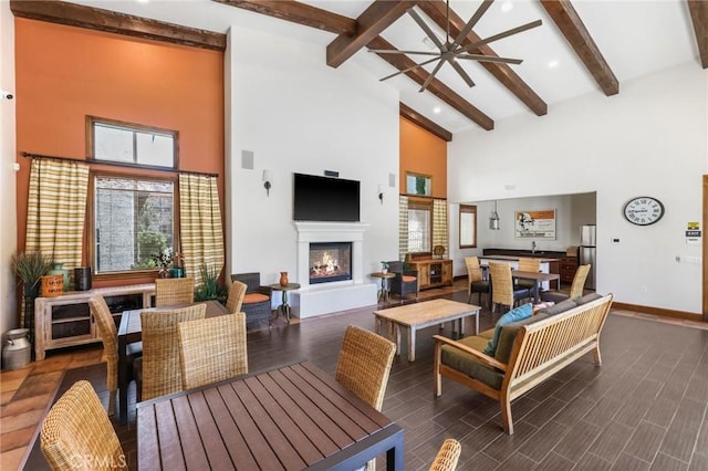 living room with ceiling fan, high vaulted ceiling, and beamed ceiling