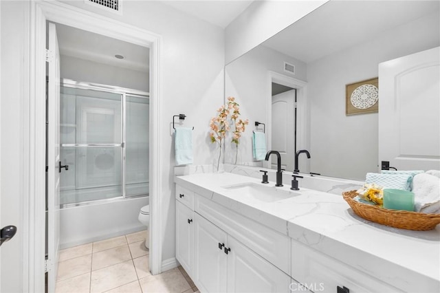 full bathroom with toilet, vanity, bath / shower combo with glass door, and tile patterned flooring