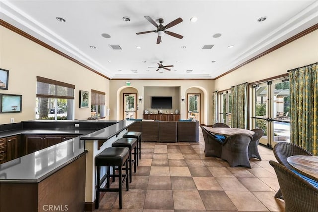 kitchen featuring crown molding, a healthy amount of sunlight, a kitchen breakfast bar, and light tile patterned floors