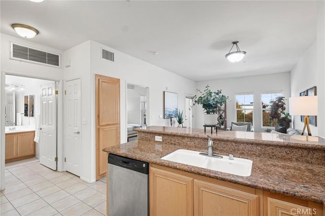 kitchen with dishwasher, sink, dark stone countertops, light tile patterned floors, and light brown cabinets