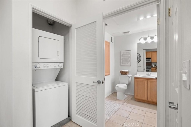 bathroom featuring stacked washing maching and dryer, toilet, tile patterned floors, and vanity