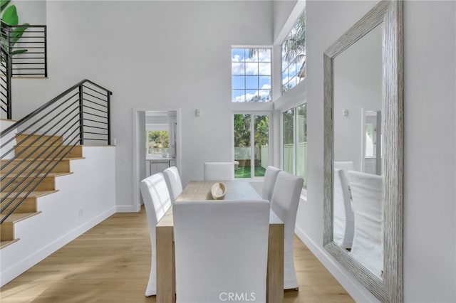 dining space featuring light wood-type flooring and a high ceiling