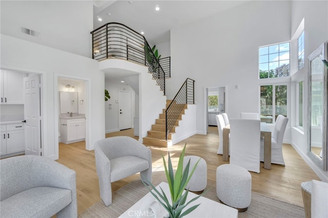 living room featuring a towering ceiling and light hardwood / wood-style floors