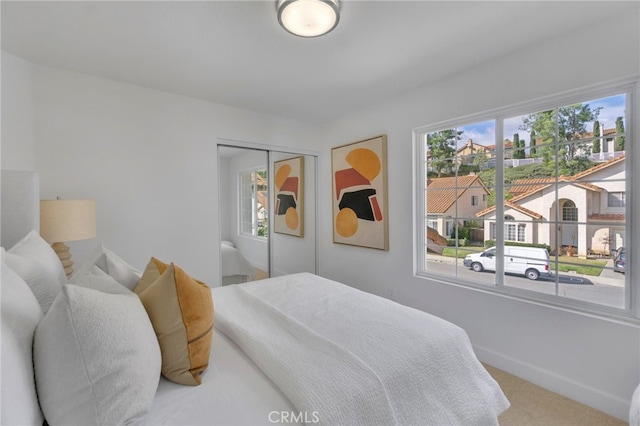 carpeted bedroom featuring multiple windows and a closet