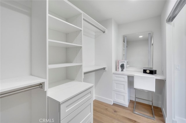 spacious closet with built in desk and light wood-type flooring