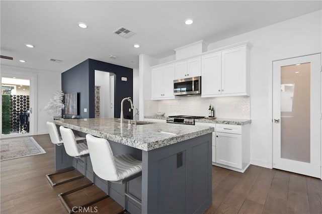 kitchen featuring sink, white cabinetry, a kitchen island with sink, a kitchen bar, and dark hardwood / wood-style flooring