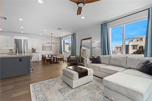 living room featuring ceiling fan with notable chandelier, sink, a wealth of natural light, and light hardwood / wood-style floors