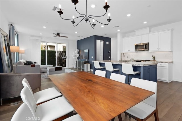 dining space with dark hardwood / wood-style flooring and ceiling fan with notable chandelier