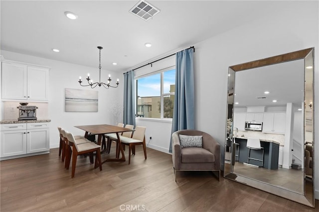 dining room with dark wood-type flooring and a notable chandelier