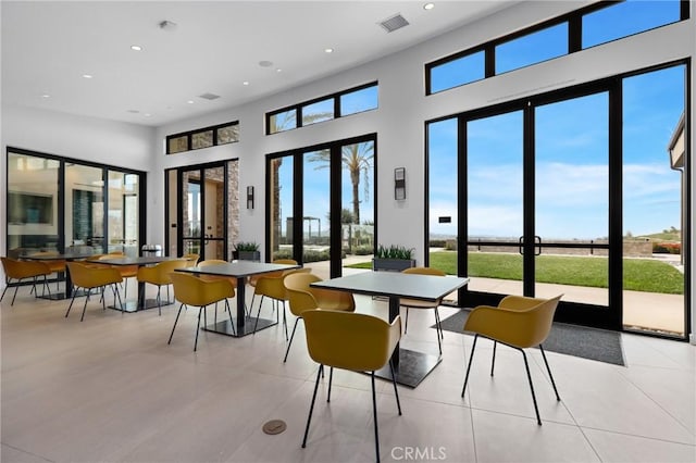 dining area with a high ceiling, light tile patterned flooring, and french doors