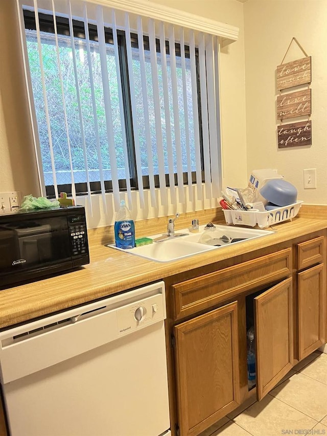 kitchen with white dishwasher, light tile patterned floors, and sink