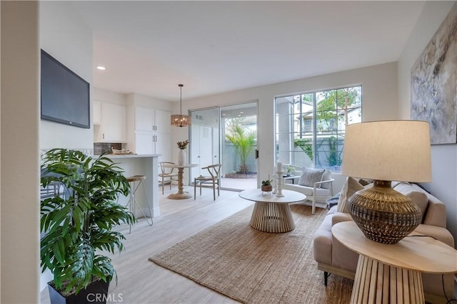 living area with an inviting chandelier and light wood-type flooring