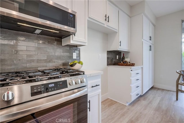 kitchen with white cabinetry, appliances with stainless steel finishes, backsplash, and light hardwood / wood-style floors