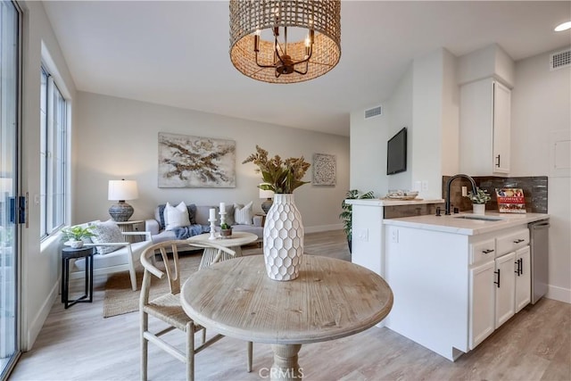 dining space with an inviting chandelier, sink, and light wood-type flooring