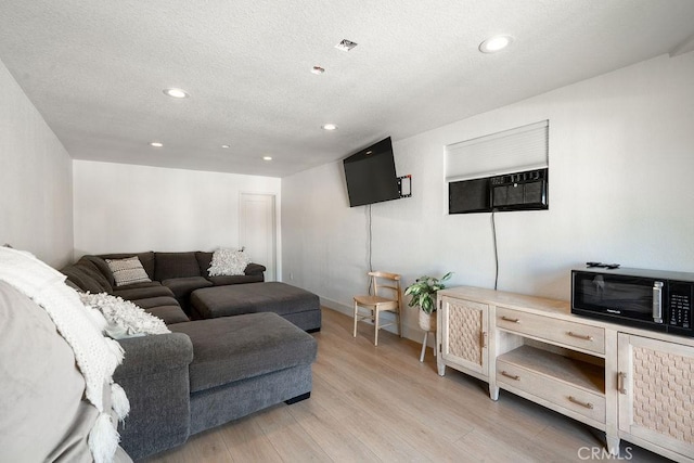 living room with light hardwood / wood-style floors and a wall mounted AC