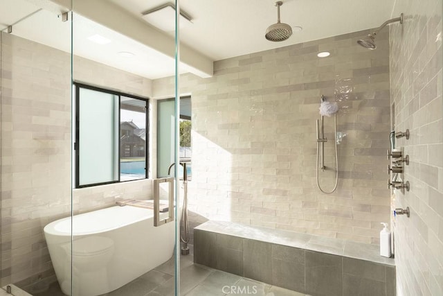 bathroom with shower with separate bathtub, tile walls, and tile patterned floors