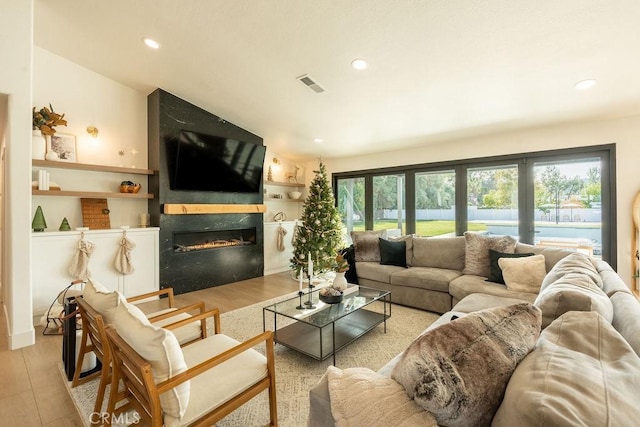 living room with a fireplace, built in shelves, light hardwood / wood-style flooring, and french doors