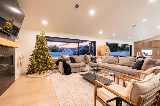 living room with a high end fireplace and light hardwood / wood-style flooring