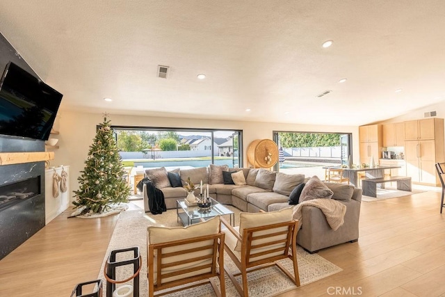 living room with a high end fireplace and light wood-type flooring