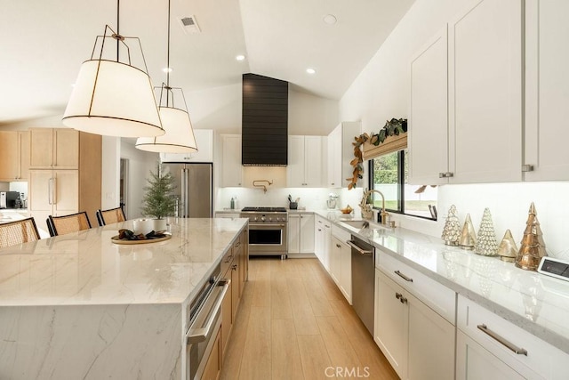 kitchen with sink, white cabinets, high quality appliances, and a kitchen island