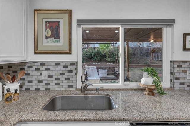 kitchen with light stone countertops, sink, decorative backsplash, and white cabinets