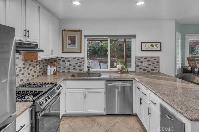 kitchen with backsplash, stainless steel appliances, sink, and white cabinets