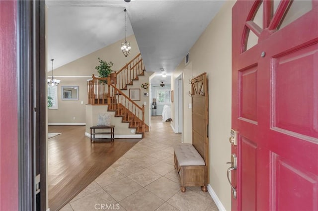 tiled entrance foyer featuring lofted ceiling and ceiling fan with notable chandelier