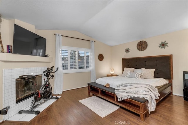 bedroom with lofted ceiling, dark hardwood / wood-style flooring, and a tile fireplace