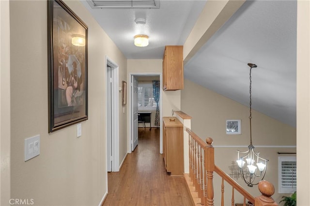 hall featuring lofted ceiling, a chandelier, and light hardwood / wood-style flooring