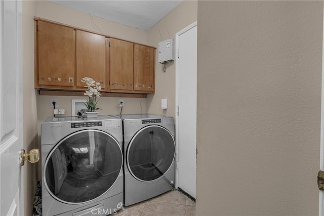 washroom featuring cabinets, washing machine and dryer, and light tile patterned floors