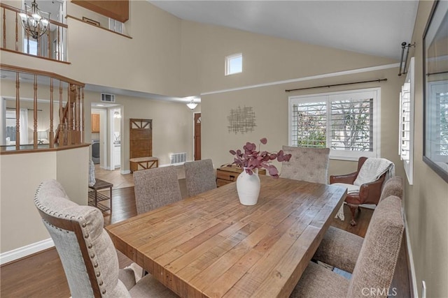 dining area featuring hardwood / wood-style flooring, a chandelier, and high vaulted ceiling