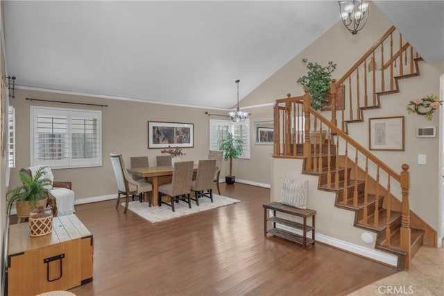 dining area with hardwood / wood-style floors, vaulted ceiling, ornamental molding, and a chandelier