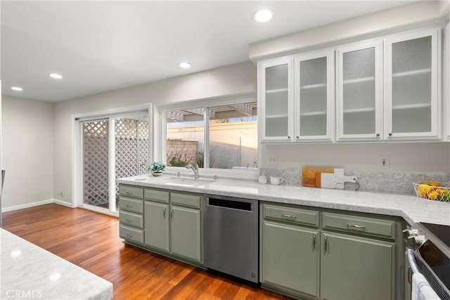 kitchen with appliances with stainless steel finishes, sink, green cabinets, and light hardwood / wood-style floors