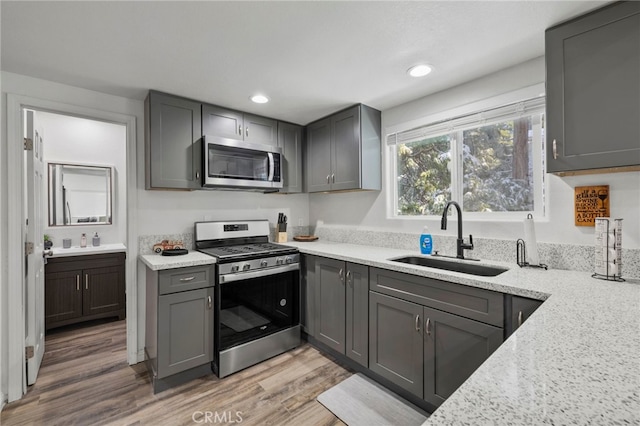 kitchen with gray cabinetry, sink, light hardwood / wood-style flooring, and stainless steel appliances