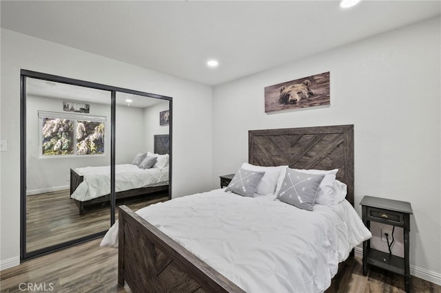 bedroom with dark hardwood / wood-style flooring and a closet