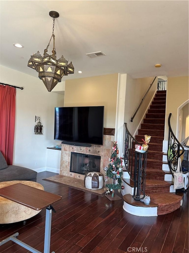 living room featuring wood-type flooring, an inviting chandelier, and a fireplace