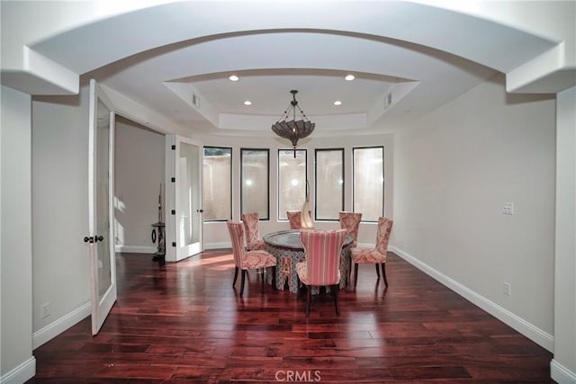 dining space featuring dark wood-type flooring and a tray ceiling