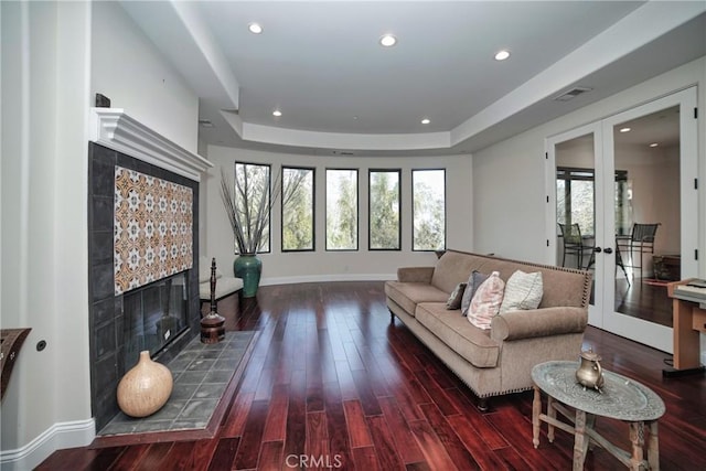 living room featuring french doors, a tray ceiling, and dark hardwood / wood-style flooring