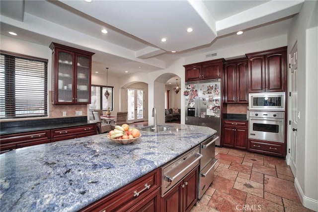 kitchen featuring pendant lighting, sink, decorative backsplash, dark stone counters, and stainless steel appliances