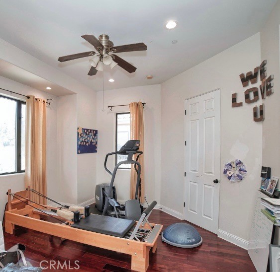 exercise room featuring ceiling fan and dark hardwood / wood-style floors