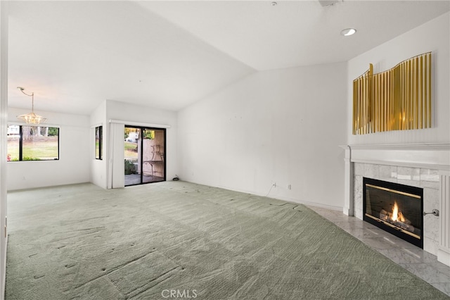 unfurnished living room with vaulted ceiling, a chandelier, light colored carpet, and a fireplace