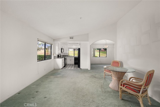 sitting room with a notable chandelier, vaulted ceiling, and light colored carpet