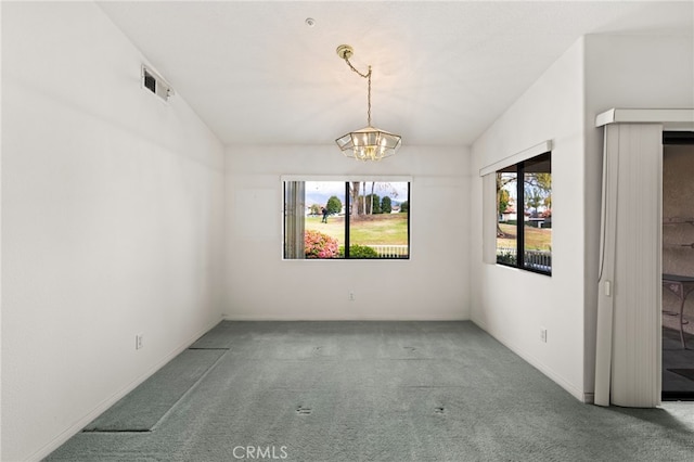 carpeted spare room with an inviting chandelier