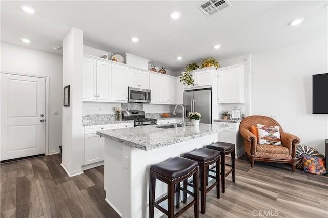 kitchen with a kitchen island with sink, white cabinets, and appliances with stainless steel finishes