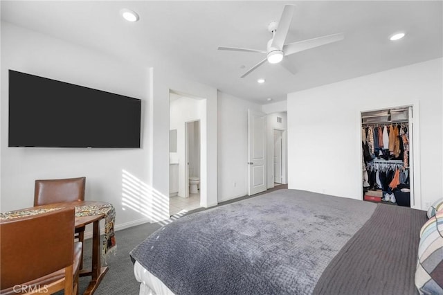 bedroom featuring ensuite bath, a walk in closet, light carpet, a closet, and ceiling fan