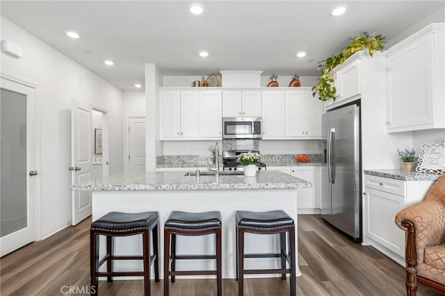 kitchen featuring stainless steel appliances, an island with sink, and white cabinets